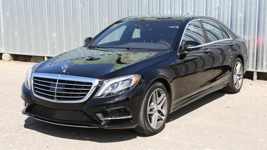 A black mercedes benz s class is parked in front of a building.