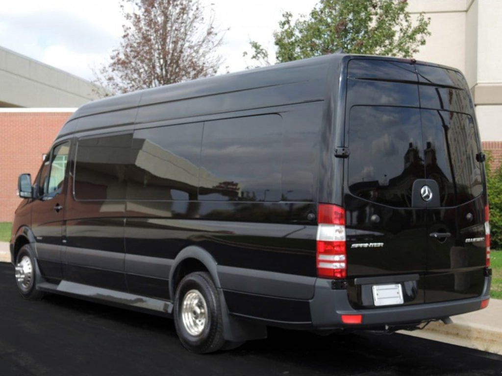 A black van is parked on the side of the road in front of a building.