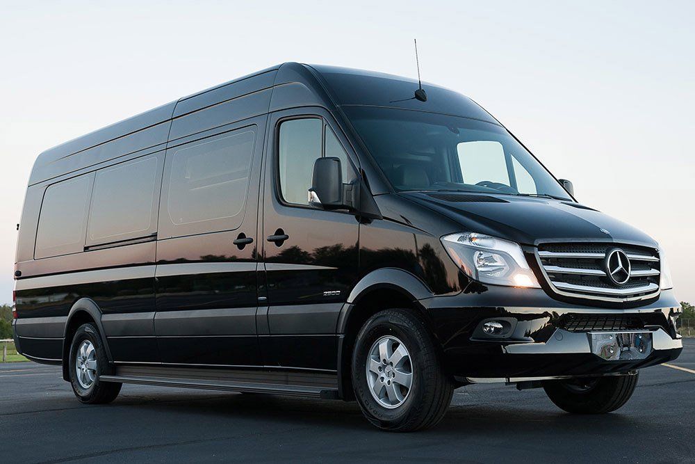 A black mercedes van is parked on the side of the road.