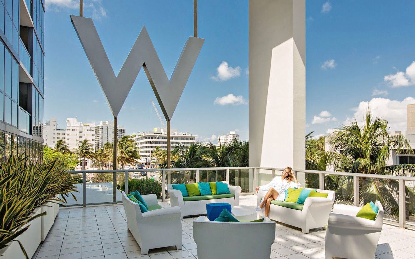 A woman is sitting on a balcony with a large w in the background.