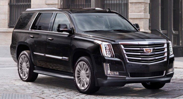 A black cadillac escalade is parked on a cobblestone street in front of a building.