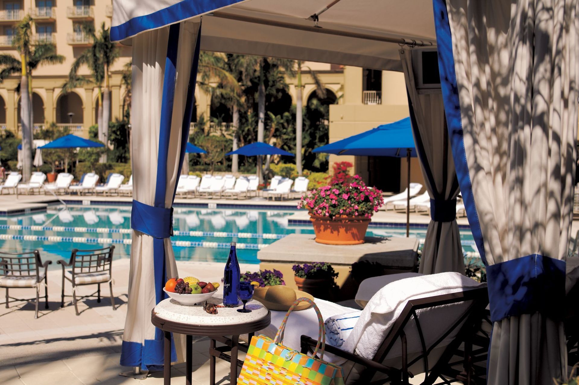 A cabana with a table and chairs in front of a swimming pool