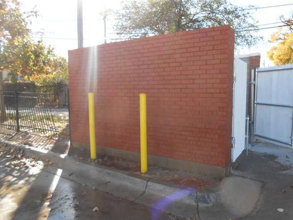 A red brick wall with yellow poles in front of it