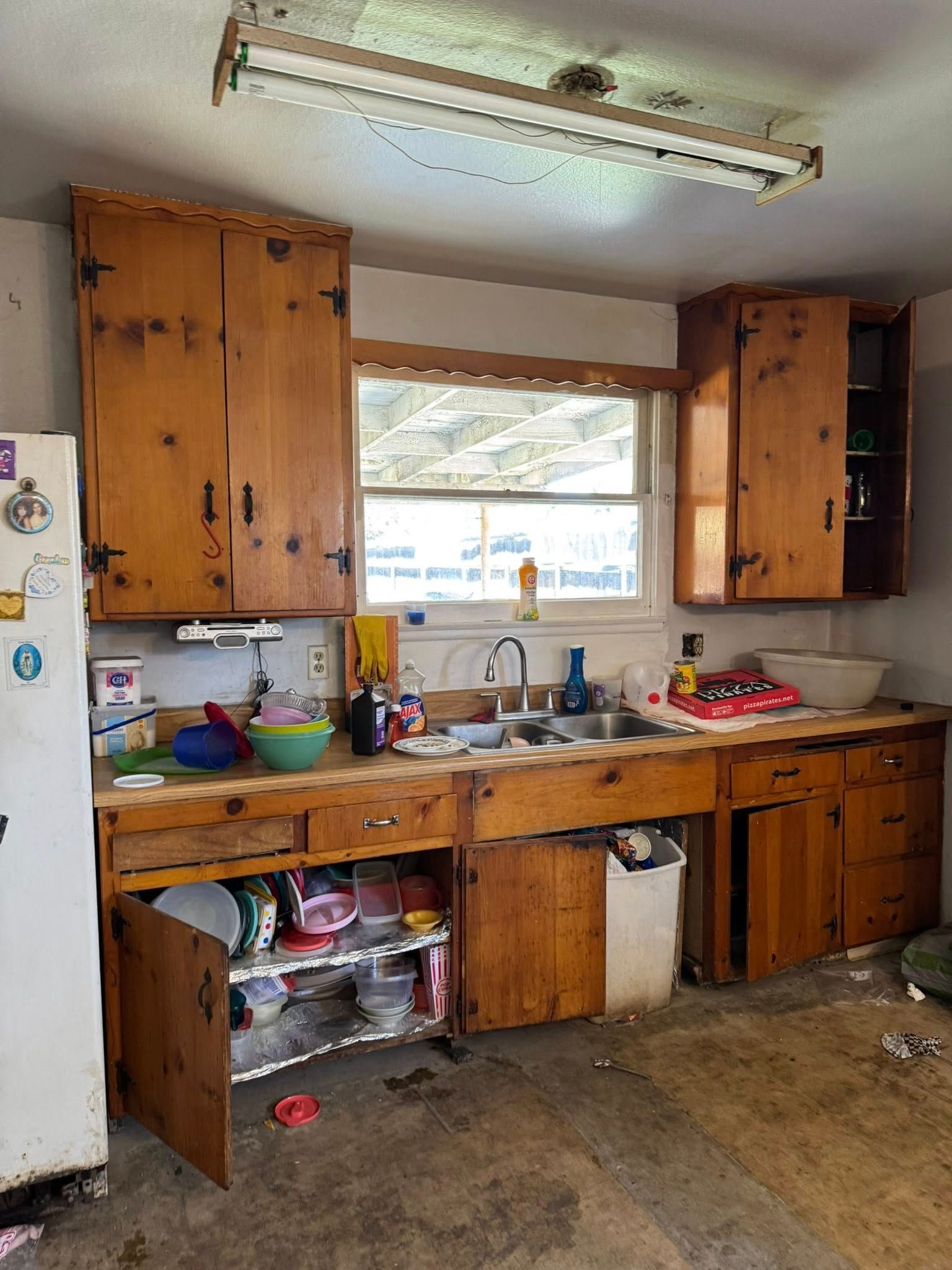Kitchen with wood cabinets, dirty counters, and a window.