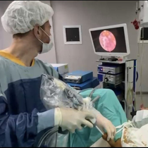 Un cirujano con uniforme quirúrgico realiza un procedimiento médico mientras mira una pantalla