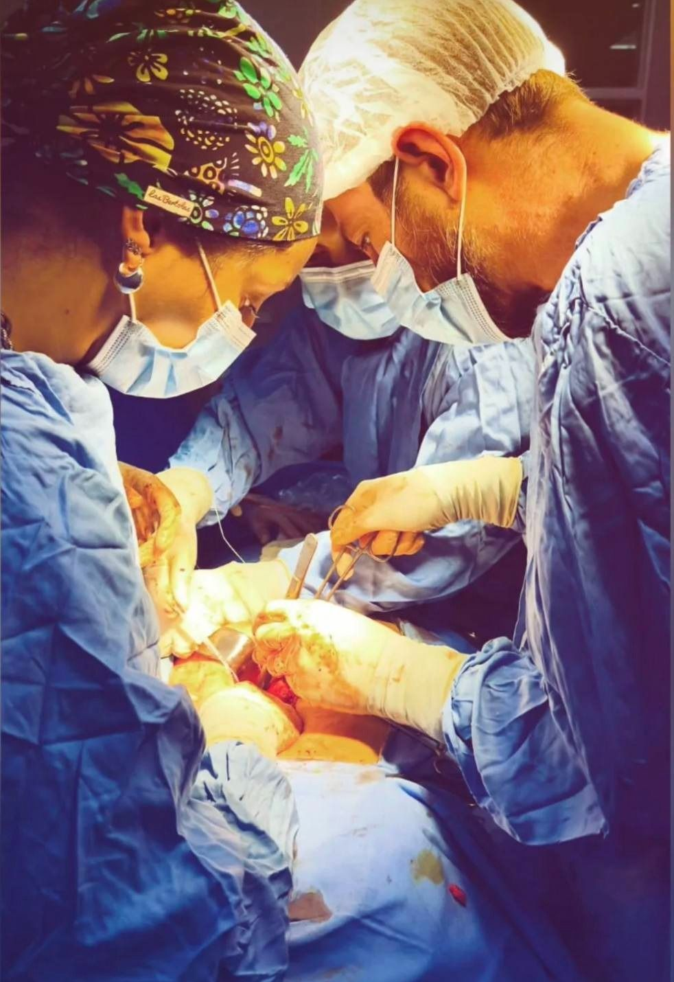Equipo médico realiza una cirugía en un quirófano bien iluminado. Las manos manipulan el instrumental quirúrgico.