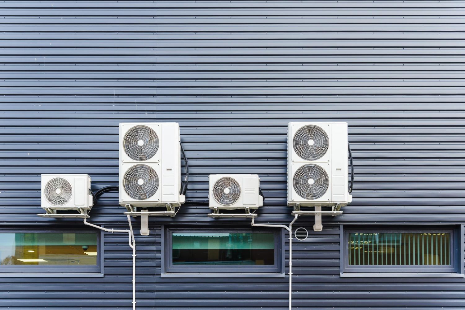 A row of air conditioners on the side of a building.