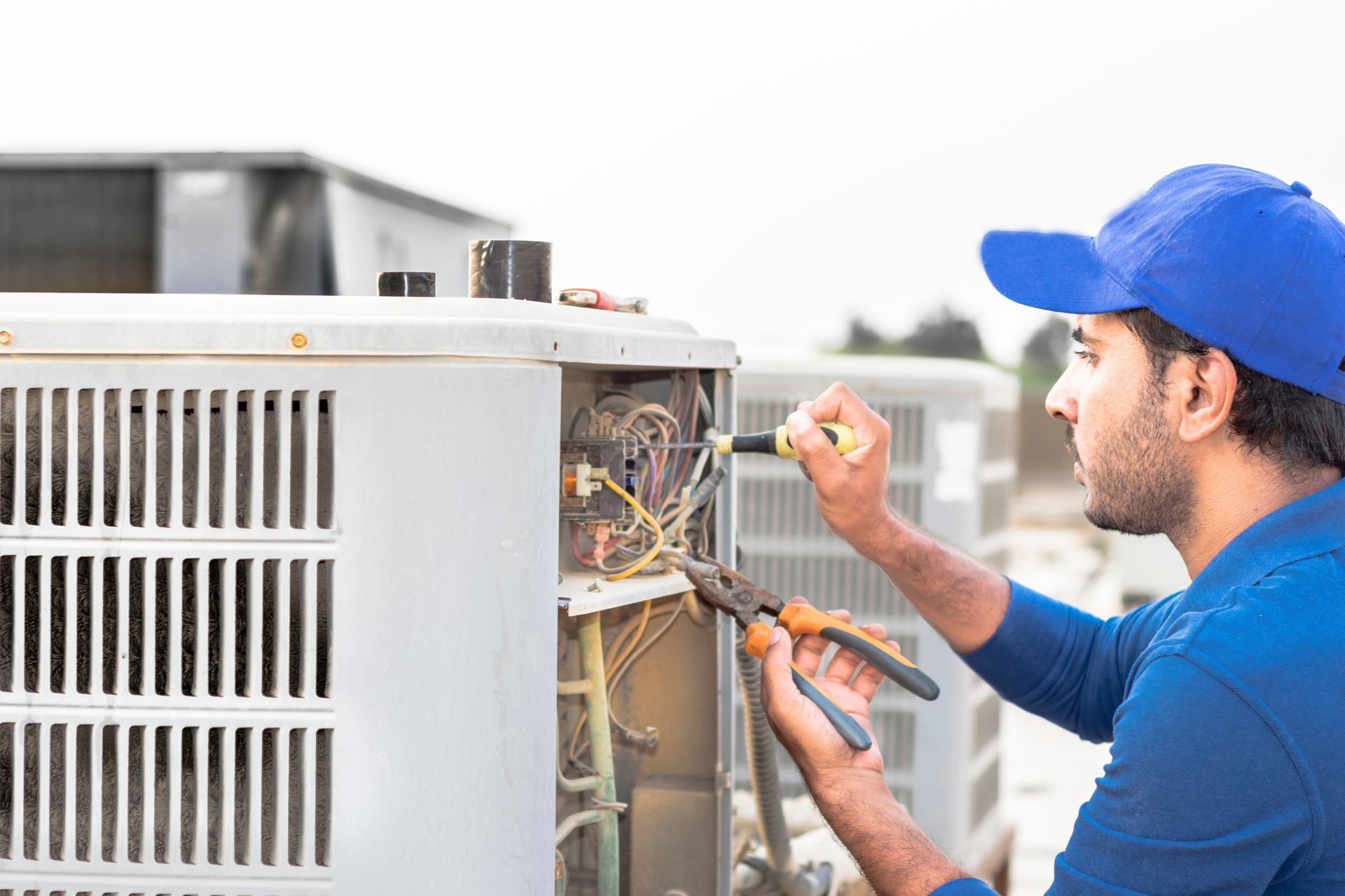 HVAC technician repairing rooftop air conditioning units
