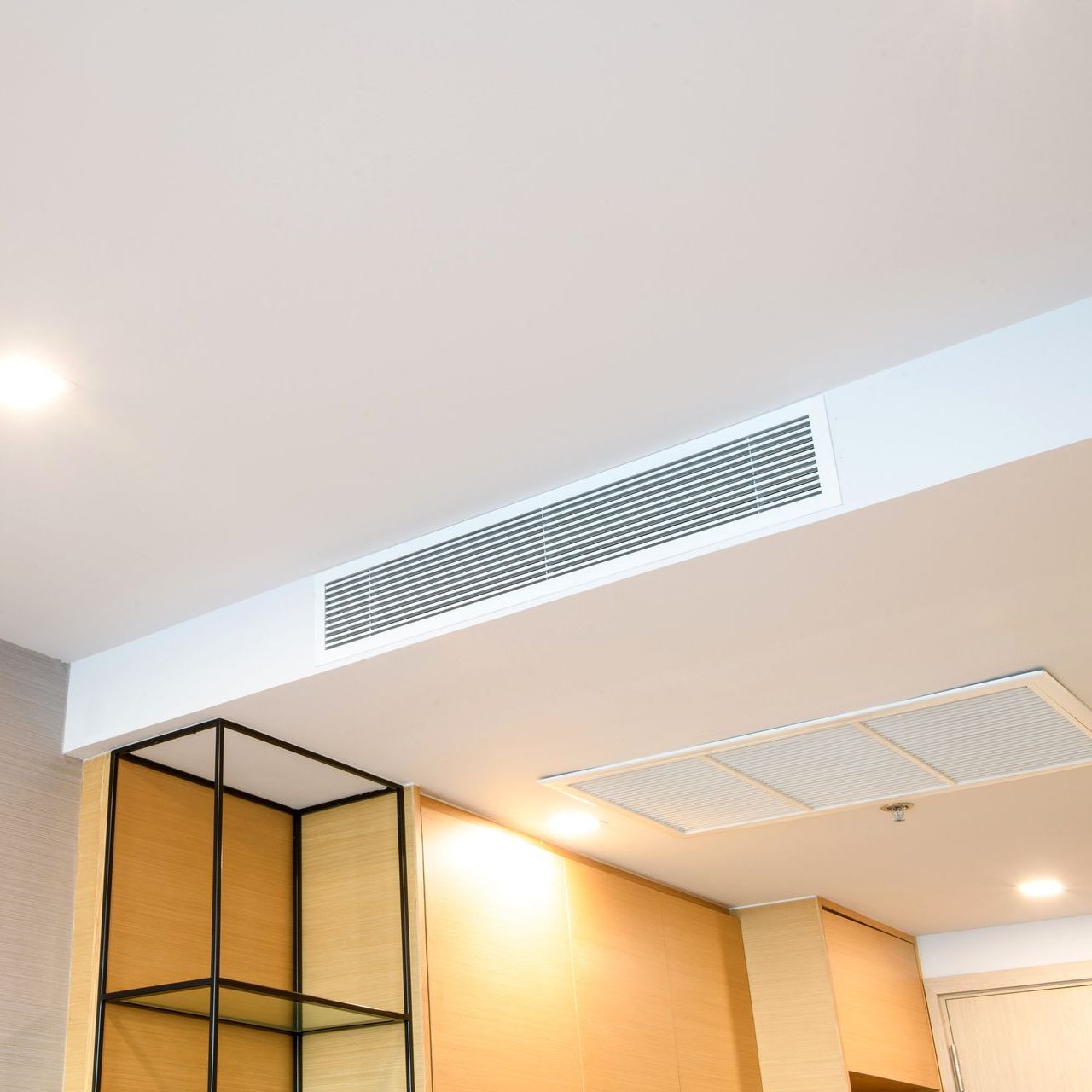White ceiling with a smoke detector, recessed lighting, and air vents. A decorative shelf and wall paneling are visible.