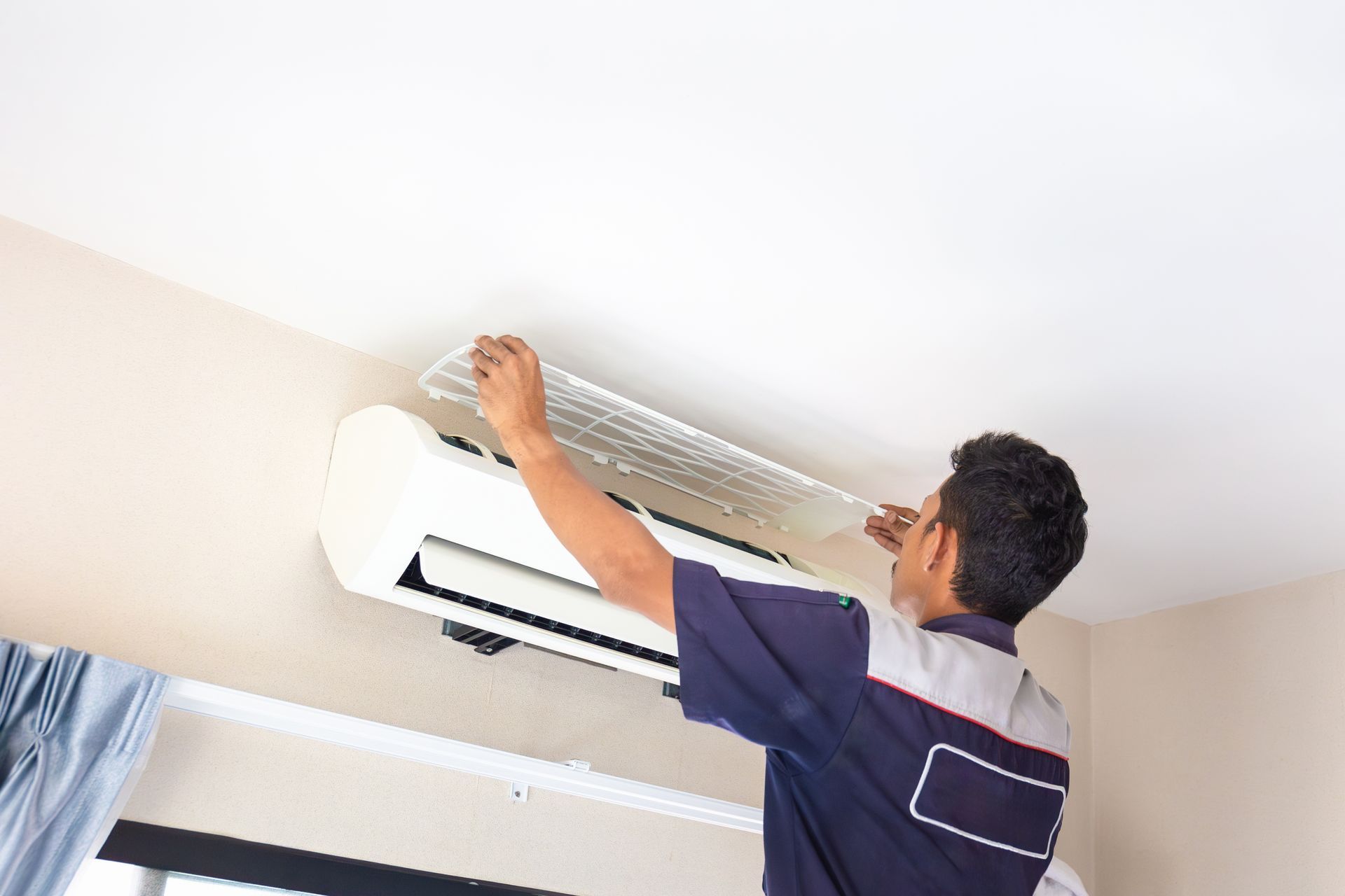 A man is installing an air conditioner on the wall.