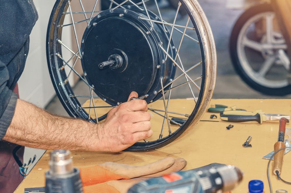 Person Fixing an Electric Bike Wheel on a Workbench — E-Go-Try-Bikes in Nelson Bay, NSW