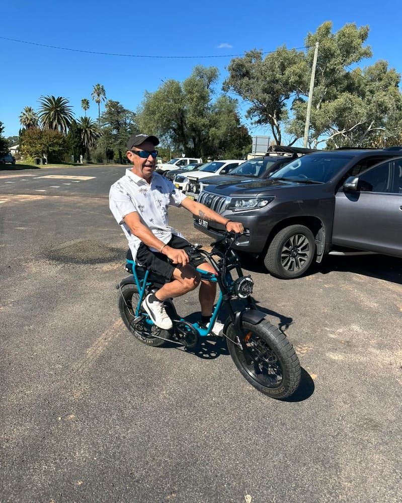 Man on a Black E-bike, Smiling in a Parking Lot Under a Sunny Sky — E-Go-Try-Bikes in Nelson Bay, NSW