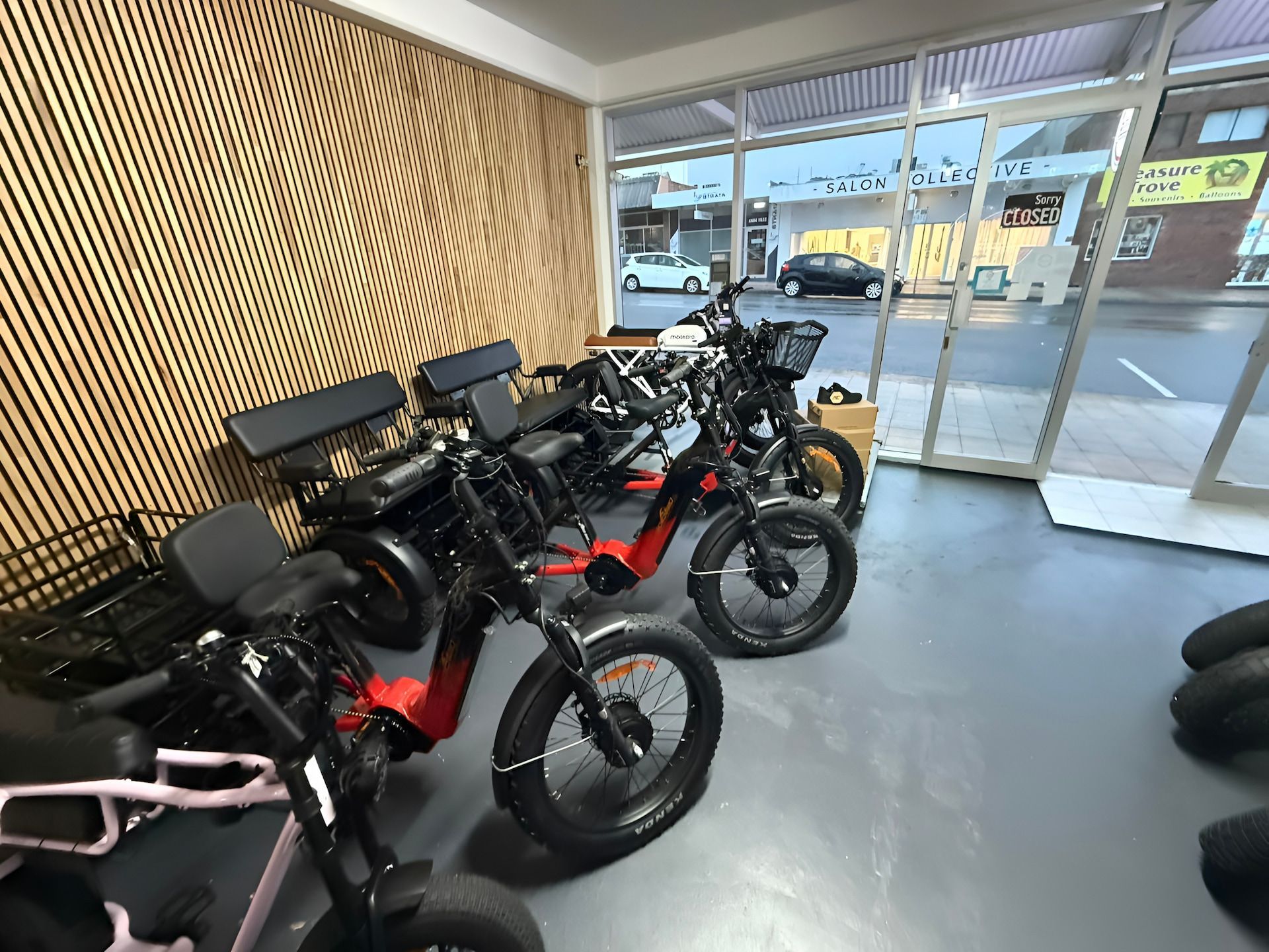 Row of Black Electric Bikes Parked Outside a Red and White Building — E-Go-Try-Bikes in Nelson Bay, NSW