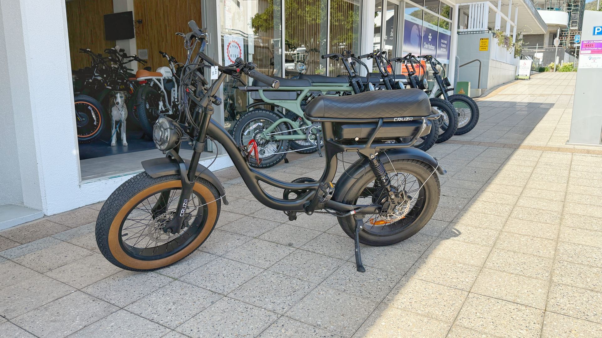 Black electric bike parked outside a shop with other bikes in the background — E-Go-Try-Bikes in Nelson Bay, NSW