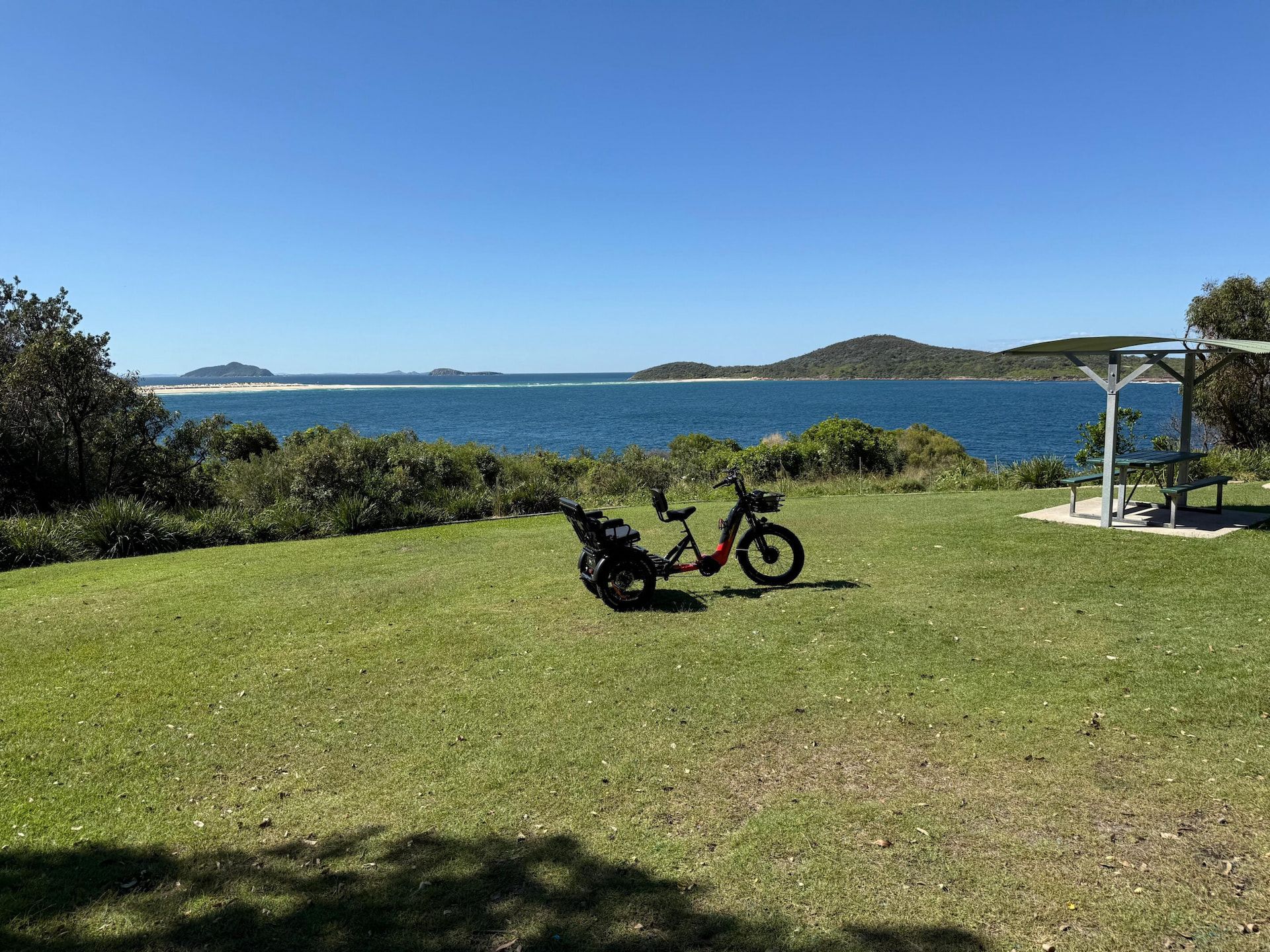 an Electric Bicycle on Grassy Lawn Overlooking a Blue Ocean — E-Go-Try-Bikes in Nelson Bay, NSW