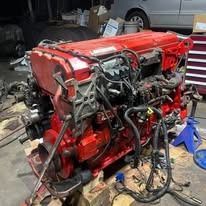 Red truck engine on a surface, with various mechanical parts and tubes attached.