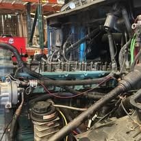 Engine of a large vehicle, showing mechanical parts and wiring in a repair shop.