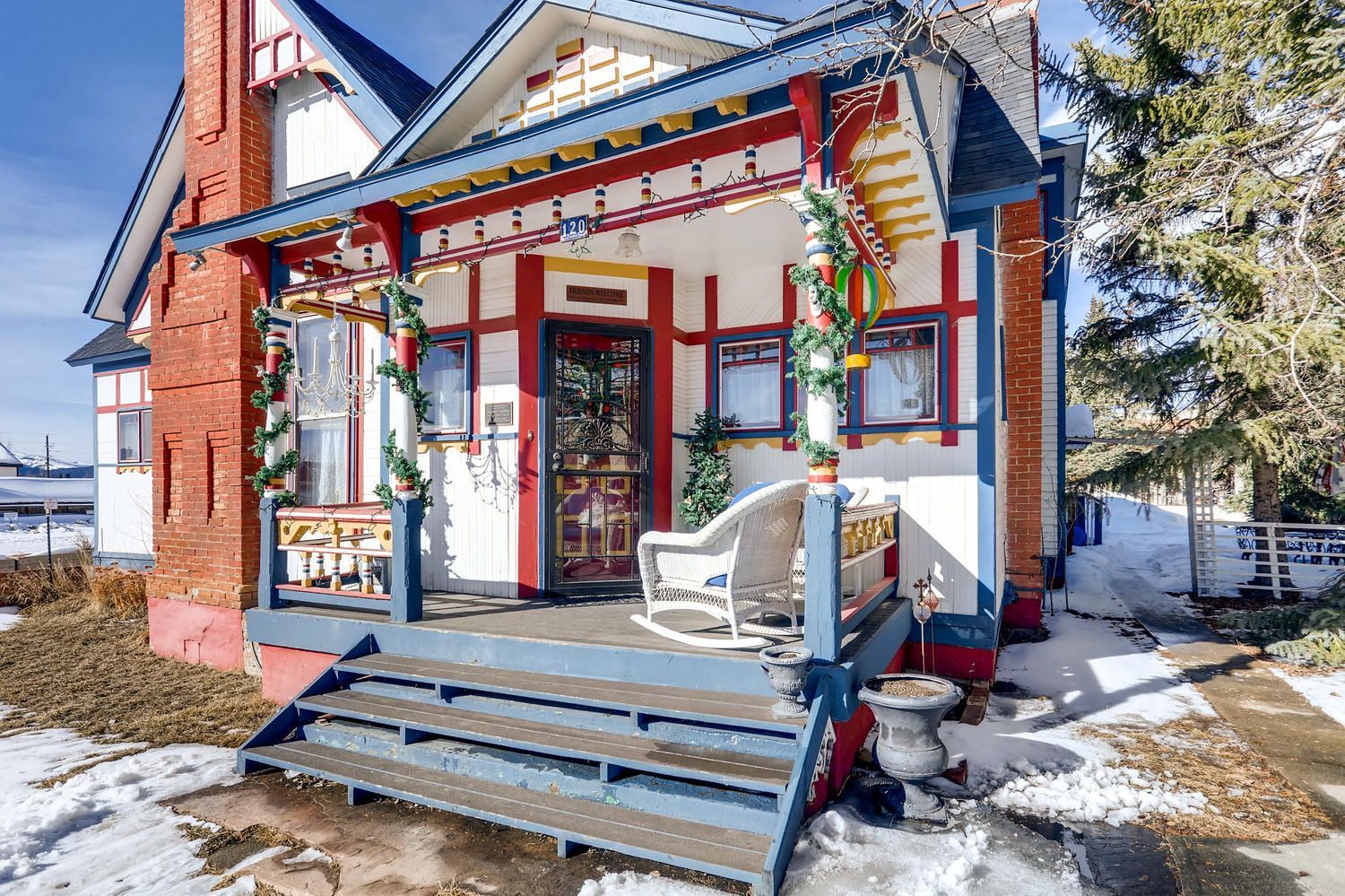 A colorful house with a porch and stairs in the snow.