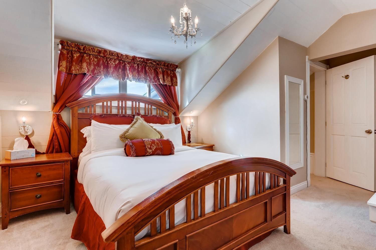 A bedroom with a king size bed , nightstand , and chandelier.