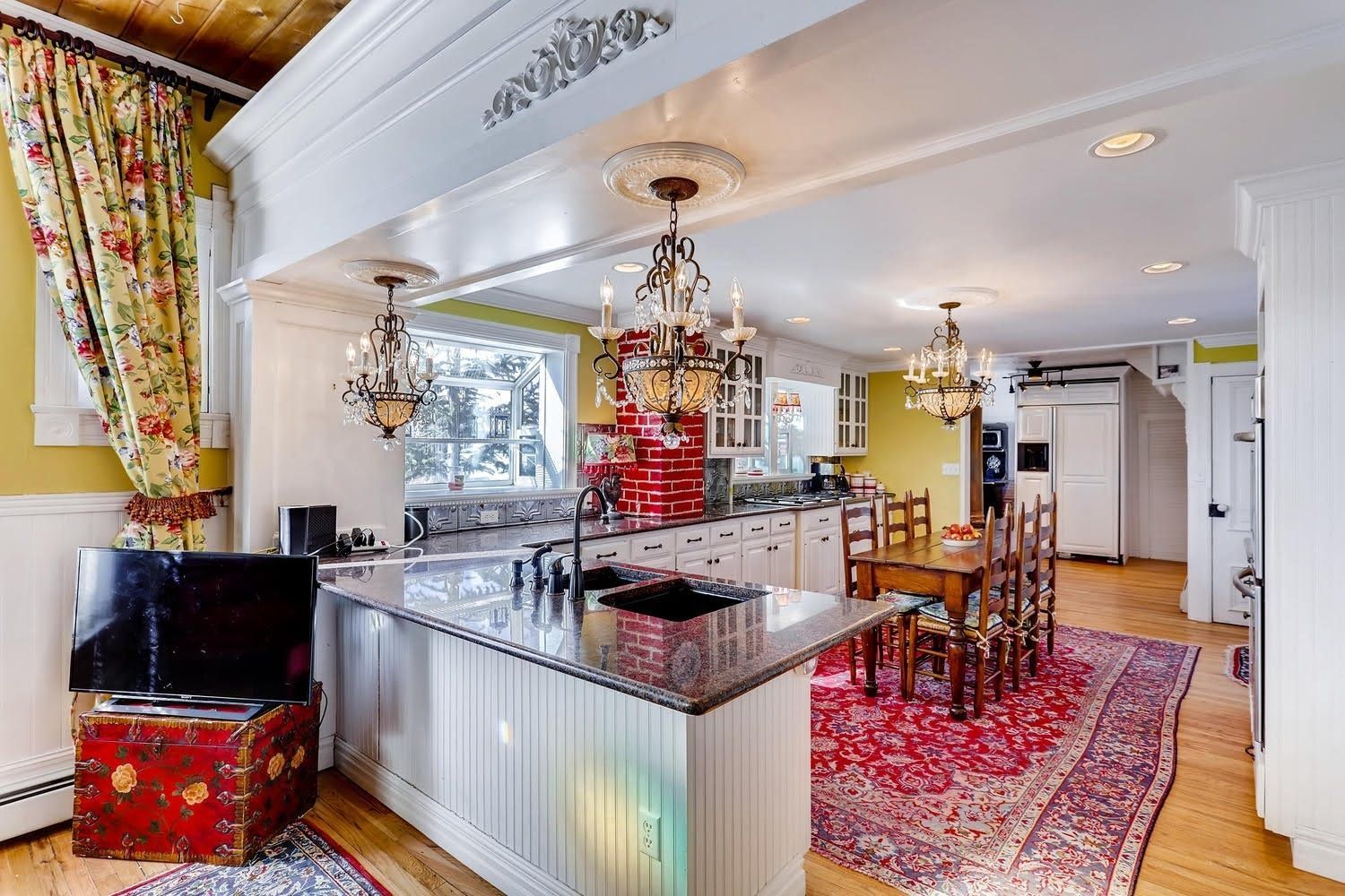 A kitchen and dining room in a house with a large island in the middle.