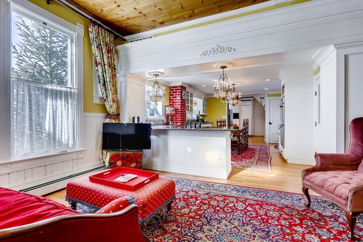 A living room with a red couch , chair , ottoman and rug.