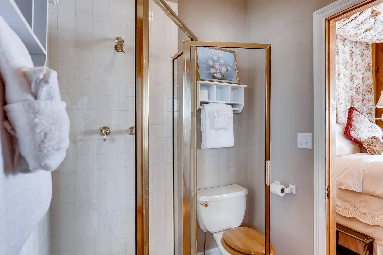 A bathroom with a toilet , shower , and towel rack.