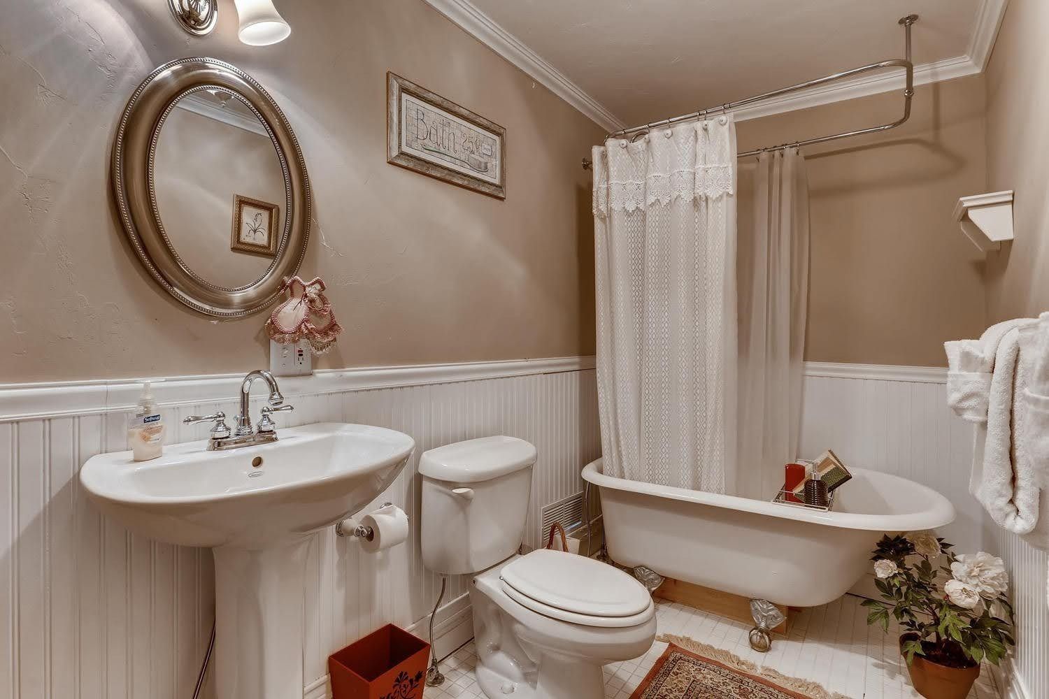 A bathroom with a sink , toilet , tub and mirror.