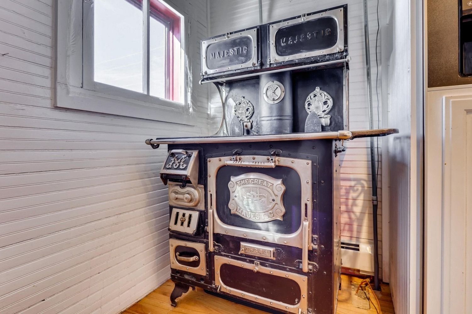 An old stove is sitting in a room next to a window.