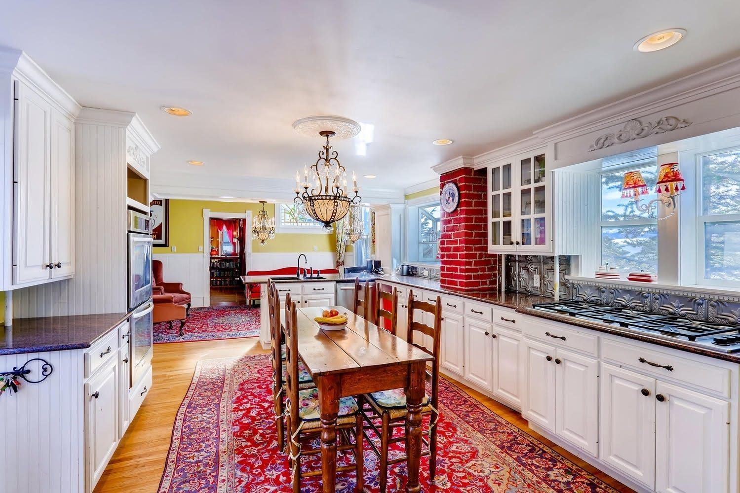 A kitchen with white cabinets and a wooden table and chairs.
