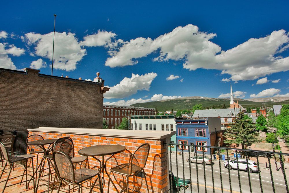 A balcony with tables and chairs overlooking a city