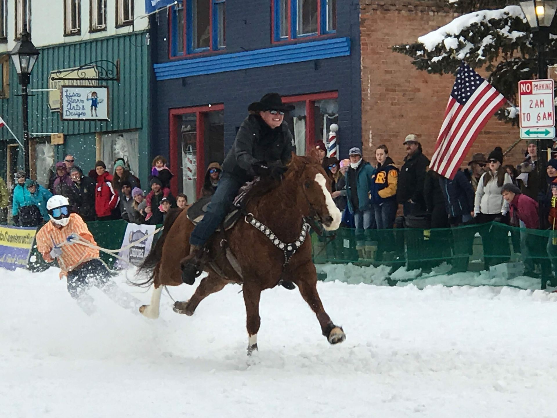 A man is riding a horse in the snow in front of a crowd.