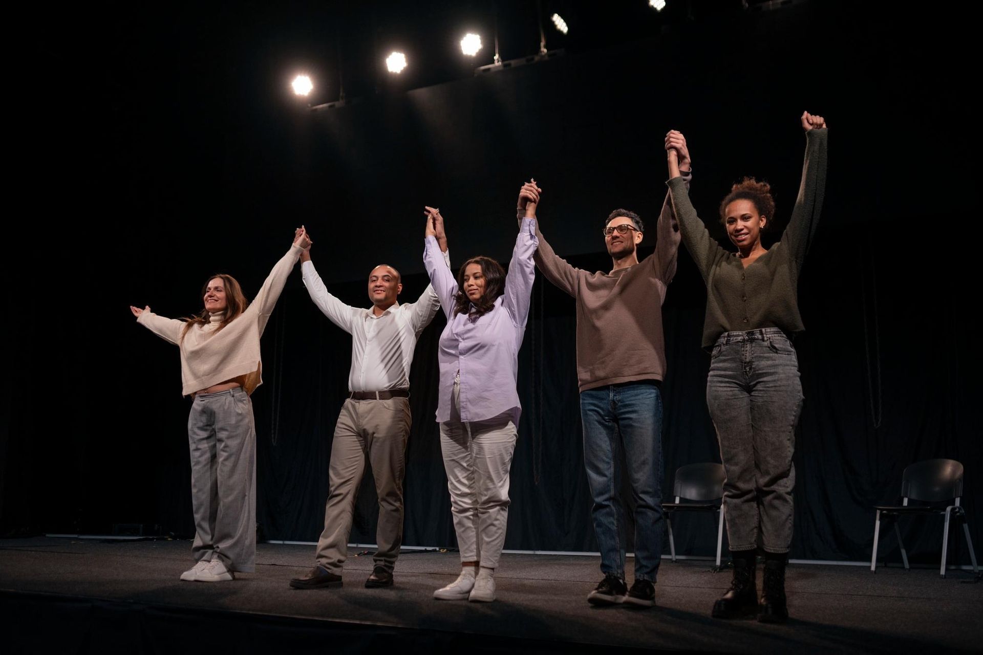 A group of people are standing on a stage with their hands in the air.