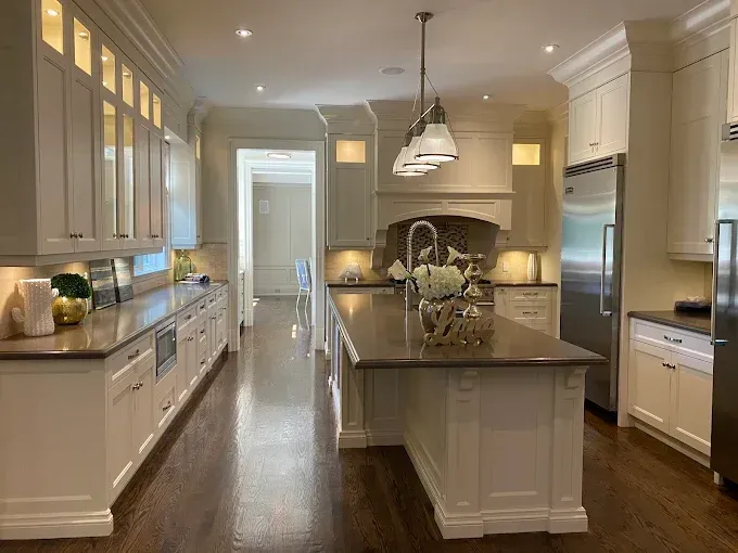 Elegant white kitchen with a large island, dark wood floors, and stainless steel appliances.