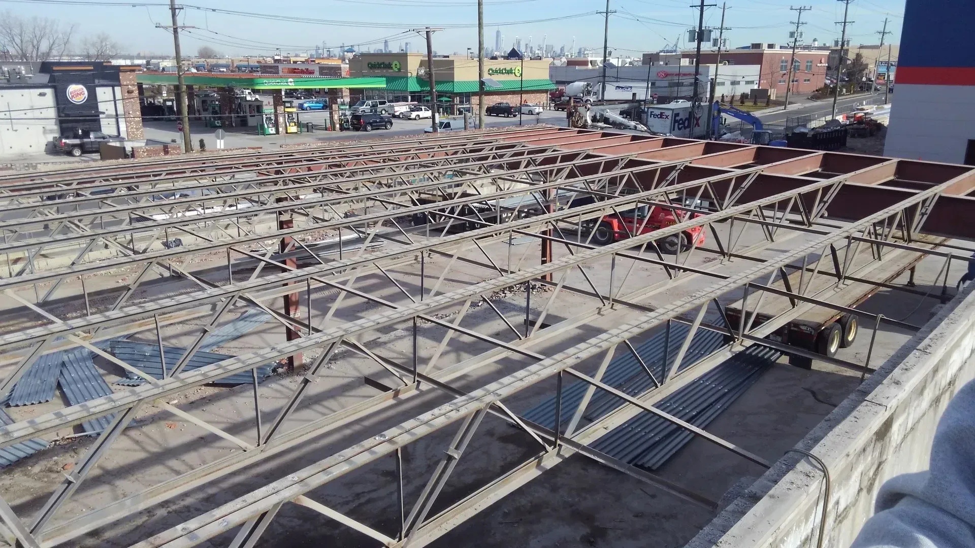 A large metal structure is being built in a parking lot.