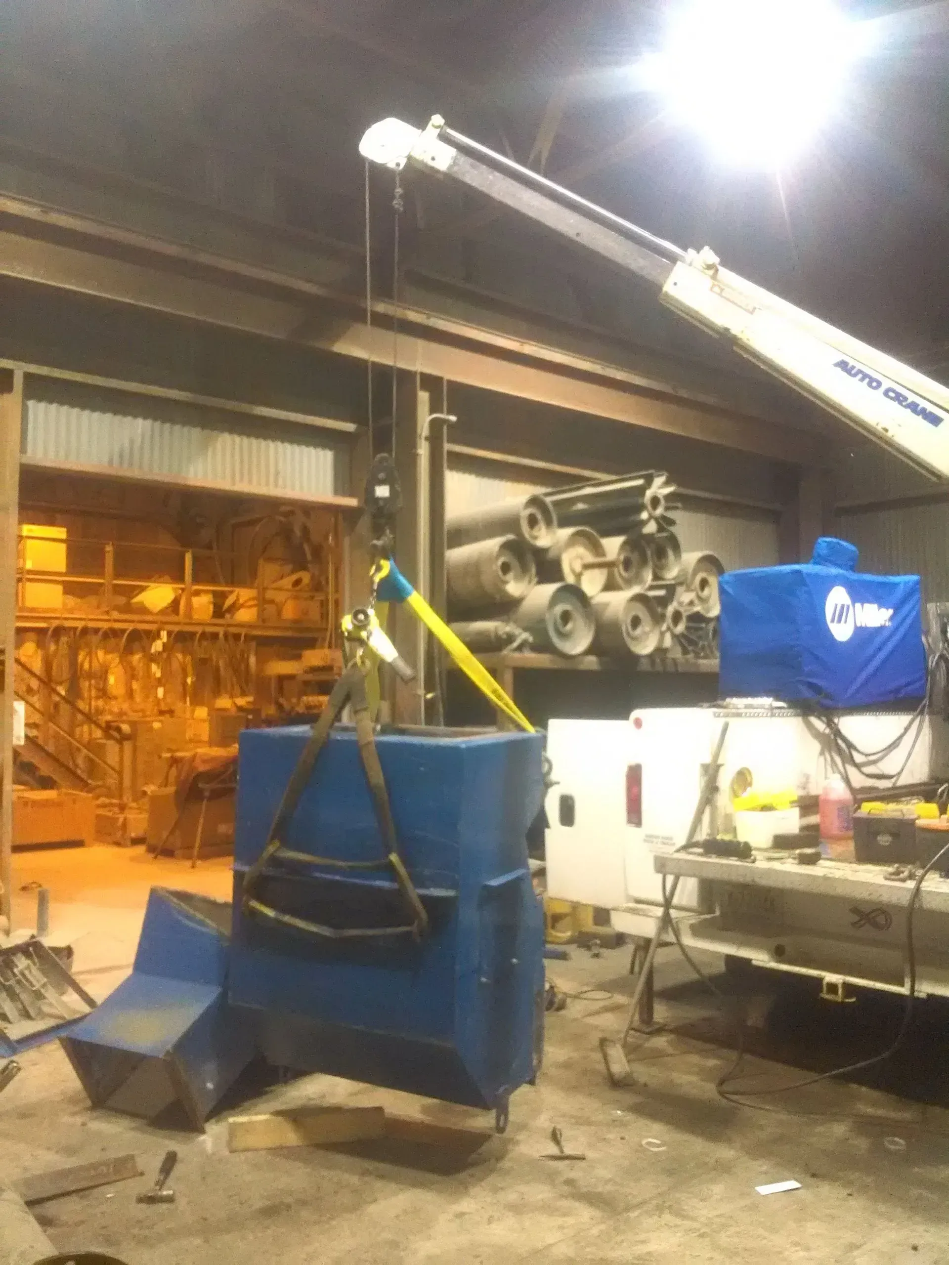 A blue bucket is being lifted by a crane in a warehouse.