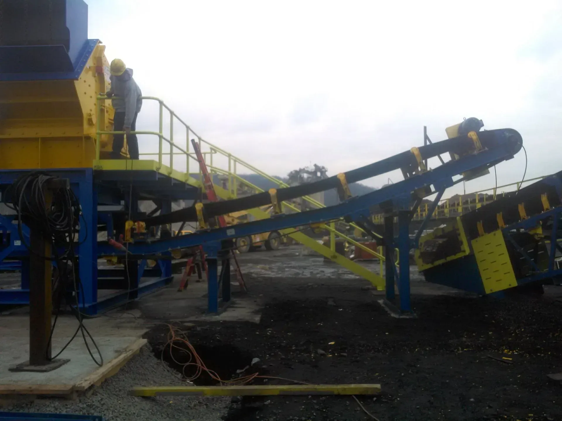A man is standing on a platform overlooking a conveyor belt.