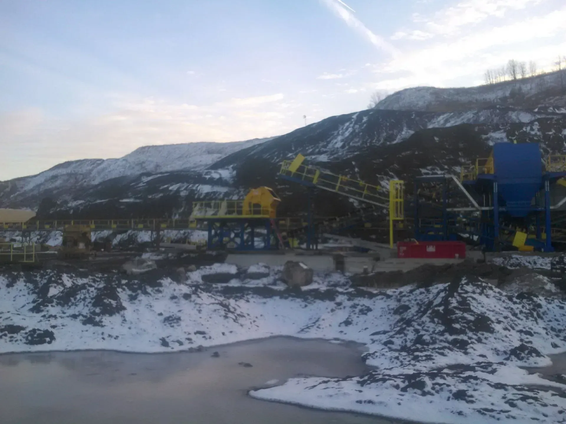 A large machine is sitting on top of a snow covered hill.