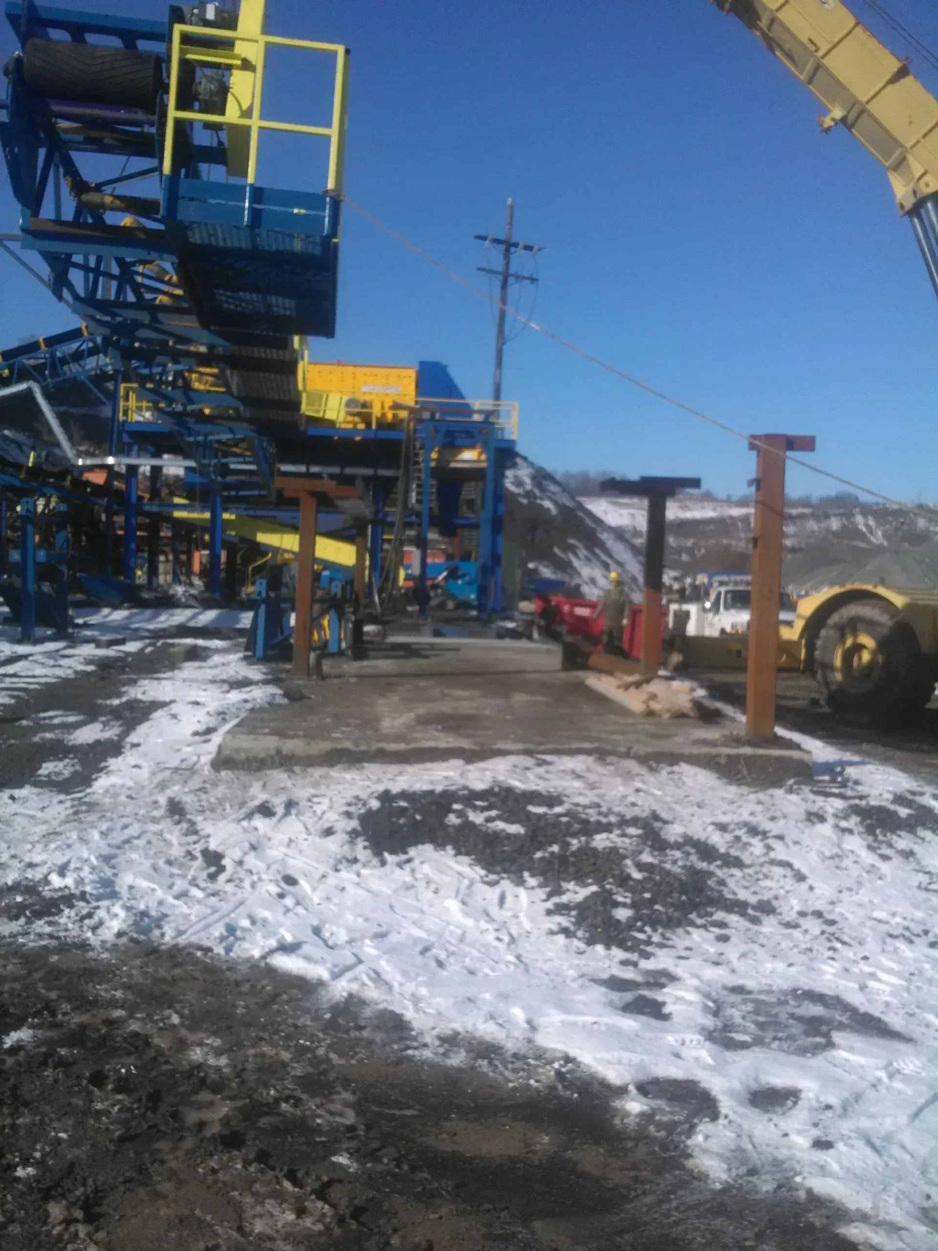 A large yellow crane is sitting on top of a snowy field.