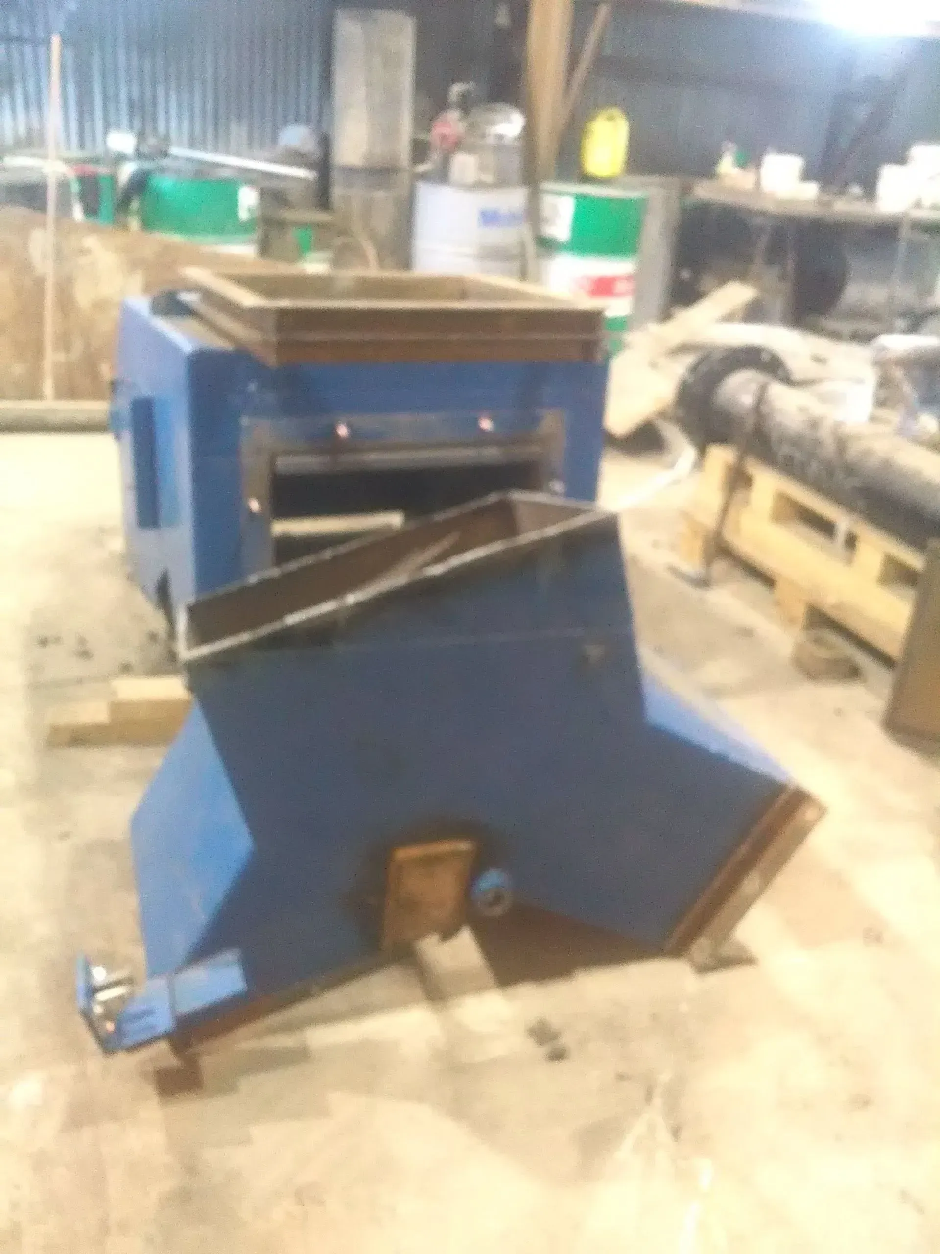 A blue machine is sitting on the floor in a warehouse.