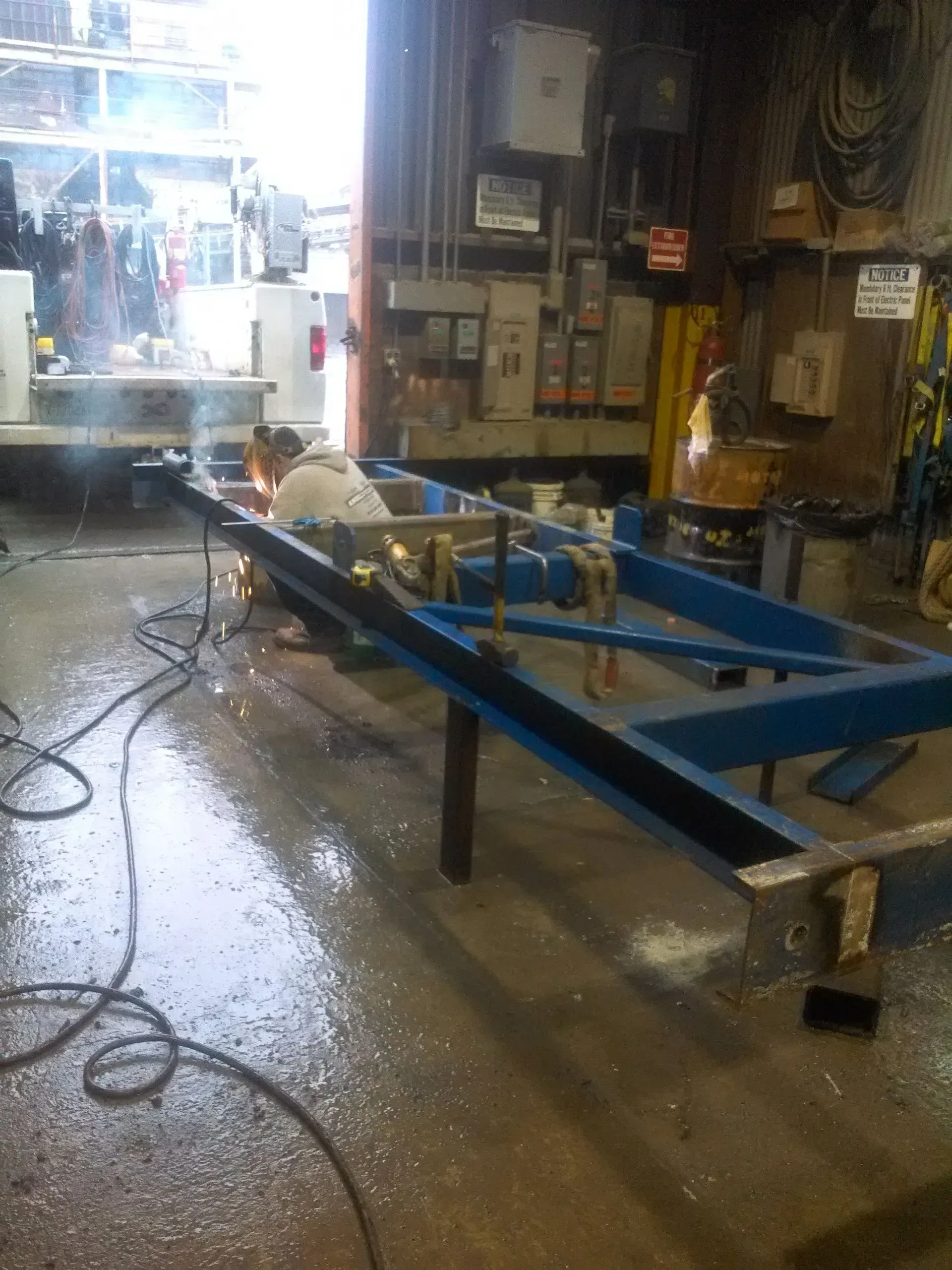 A man is welding a blue frame in a garage.