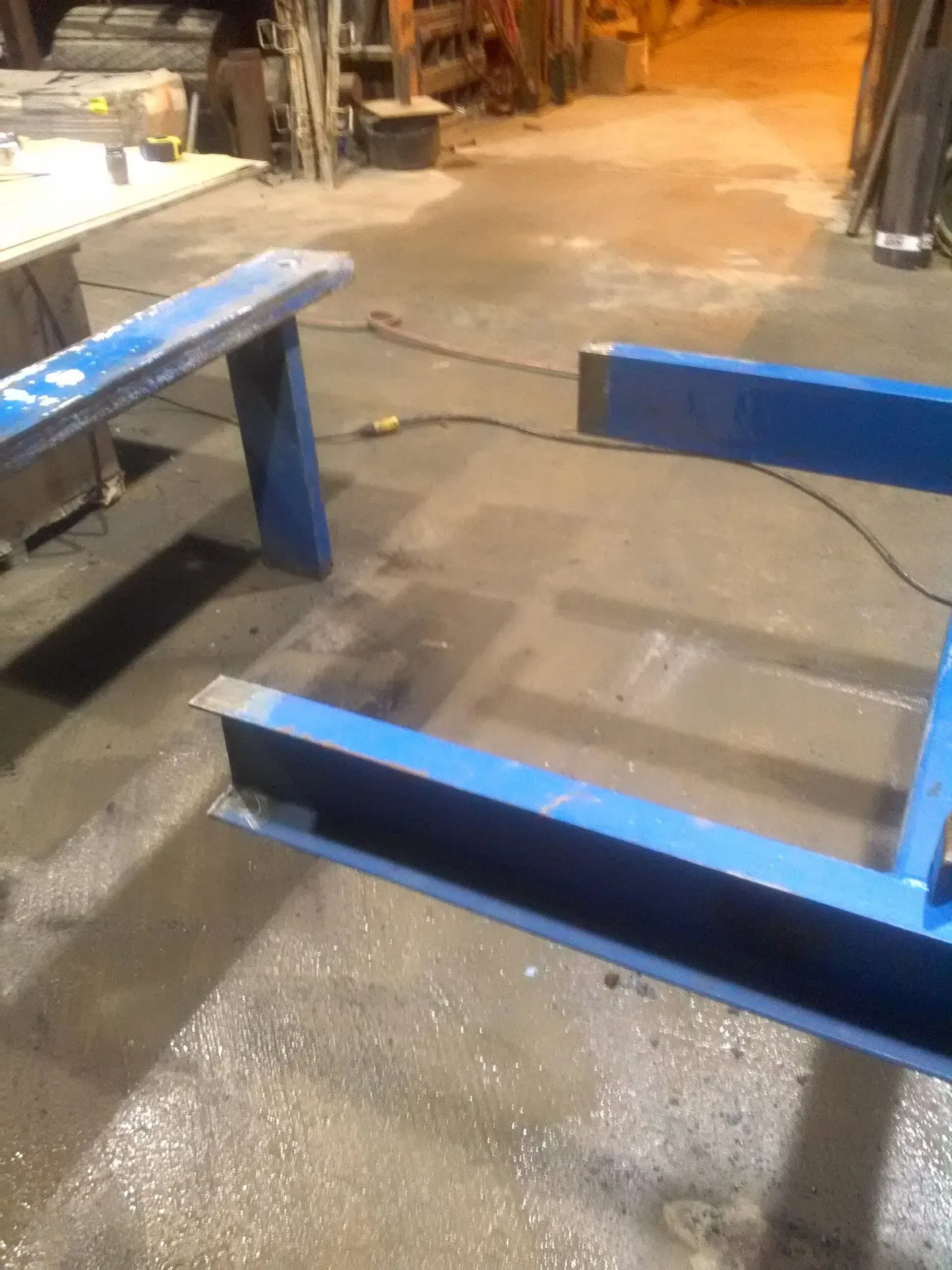 A blue metal frame is sitting on a concrete floor in a room.