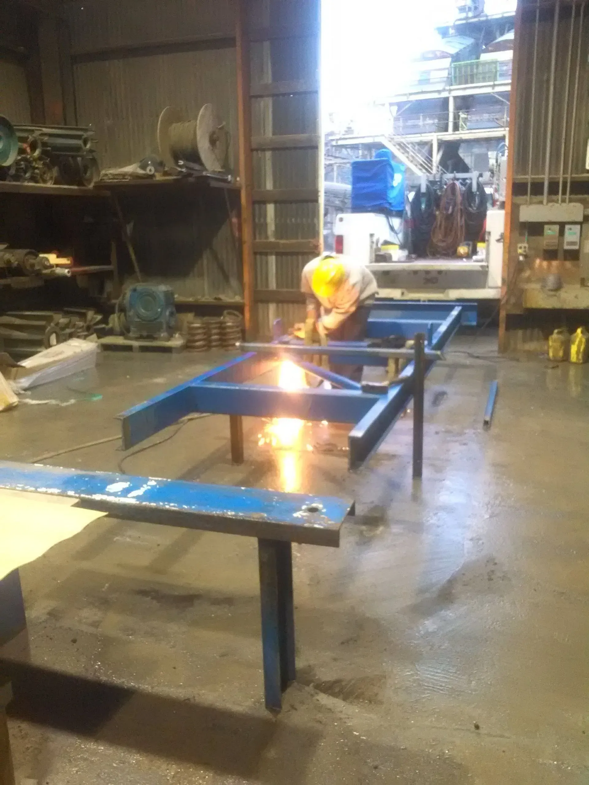 A man is welding a piece of metal in a factory.