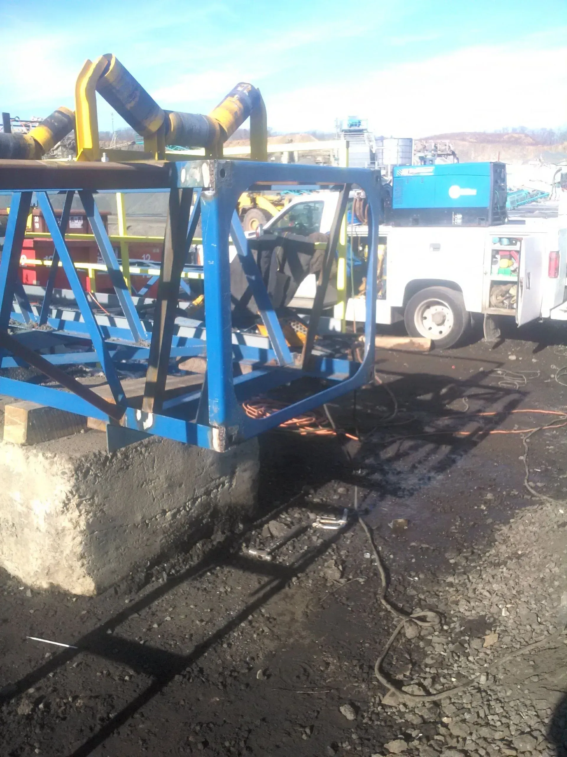 A white truck is parked next to a blue machine.