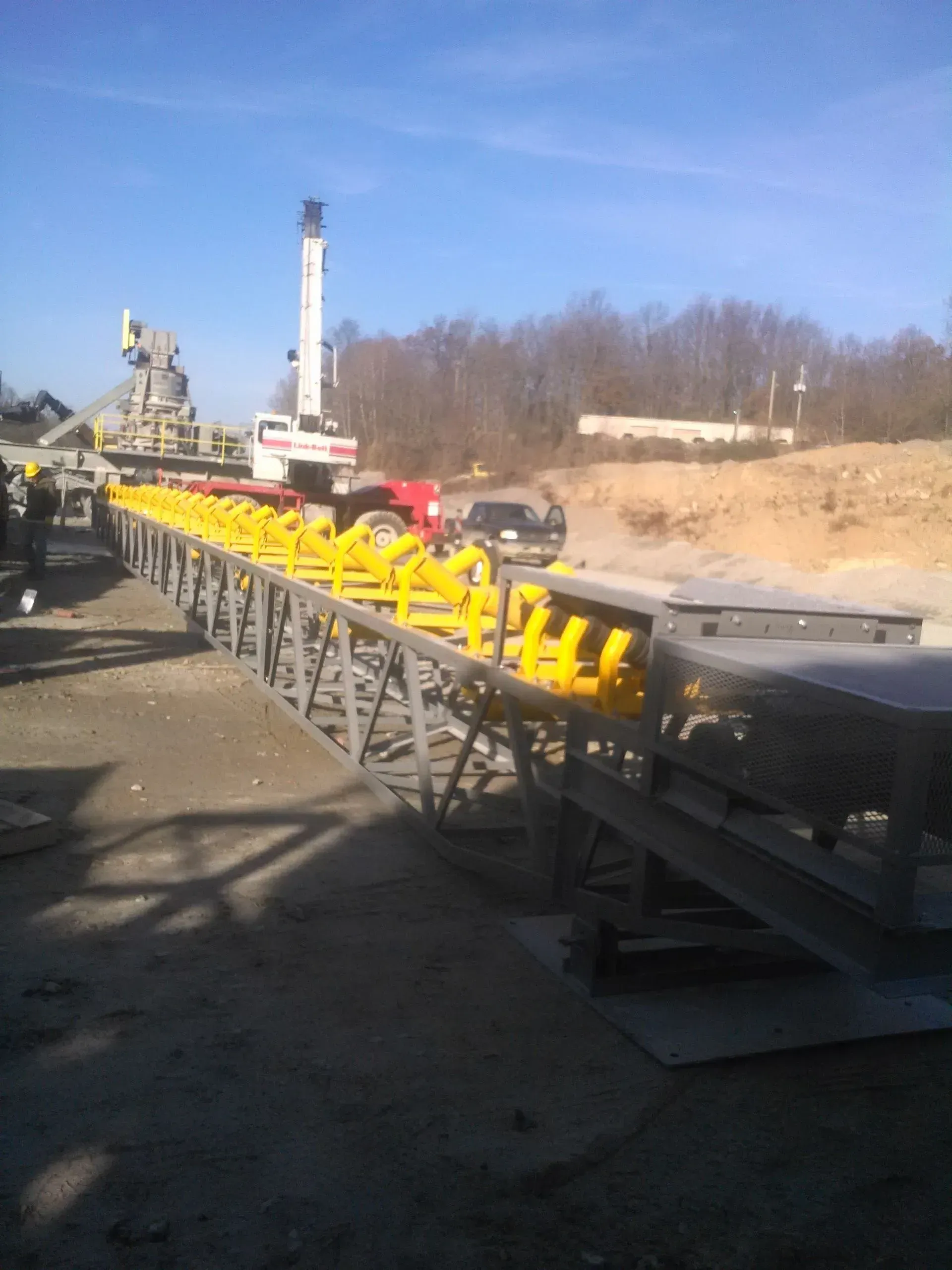 A bunch of yellow pipes are lined up on a conveyor belt.