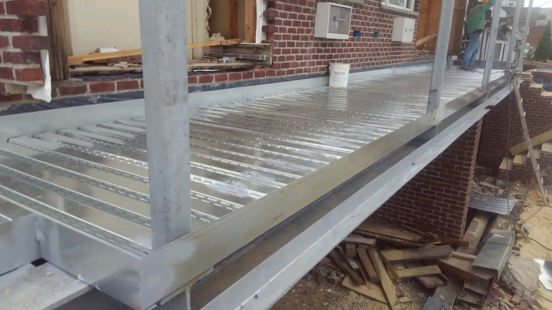 A metal deck is being built on the side of a brick building.