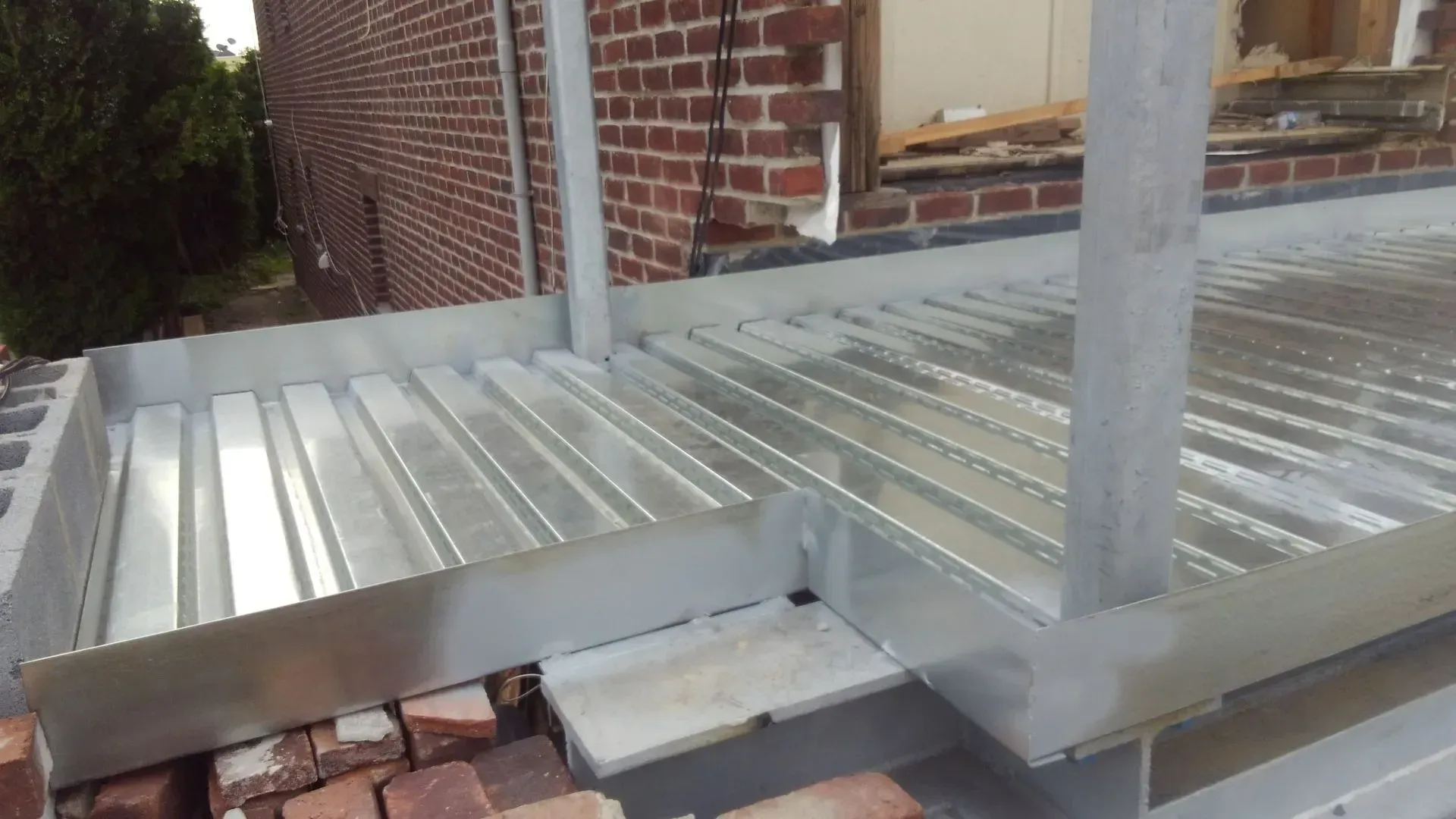 A metal deck is being built next to a brick building.