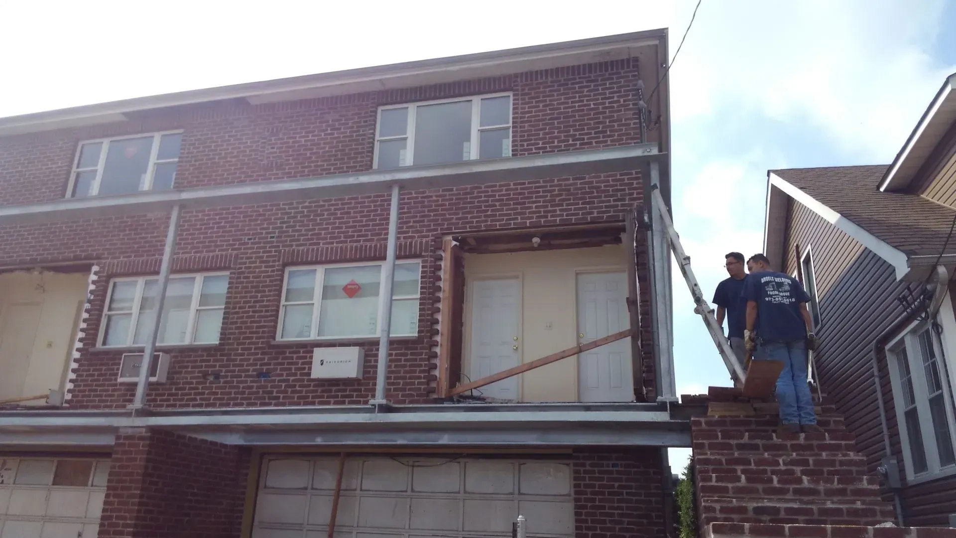 Two men are standing in front of a large brick building.