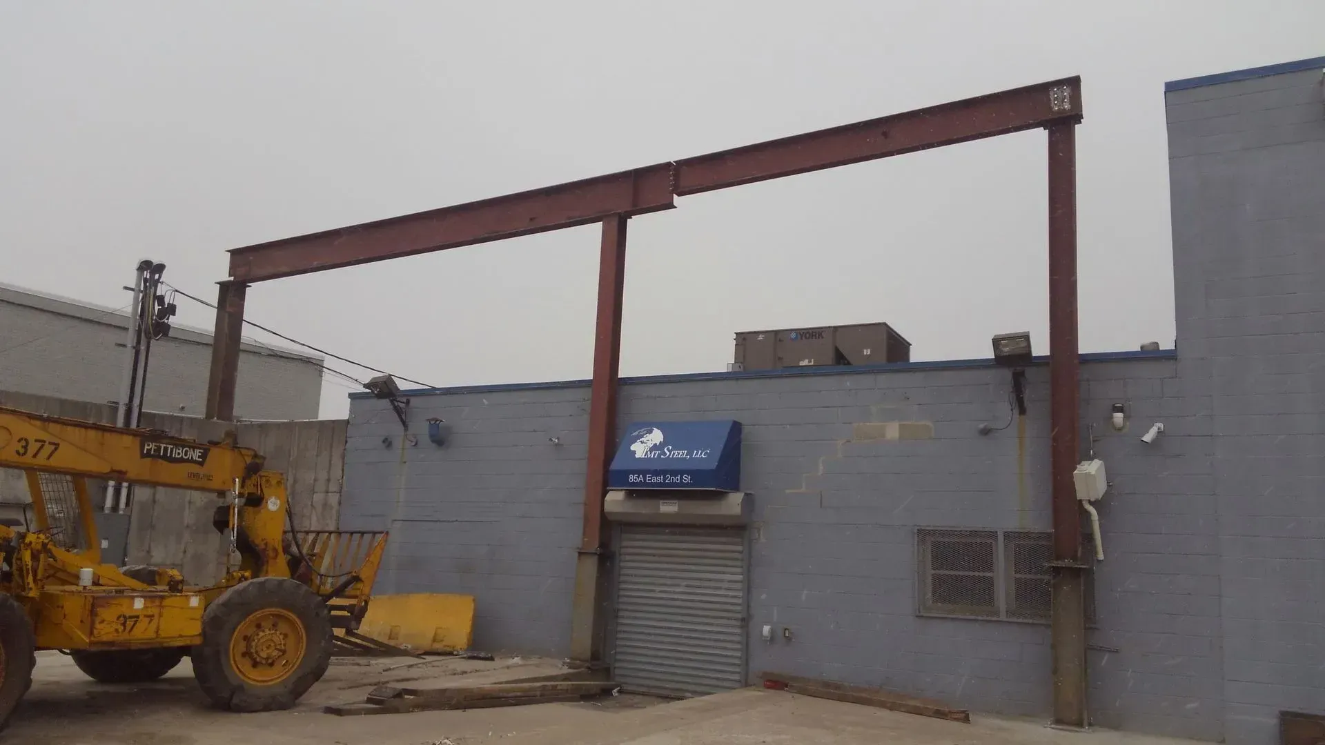 A yellow crane is parked in front of a building.