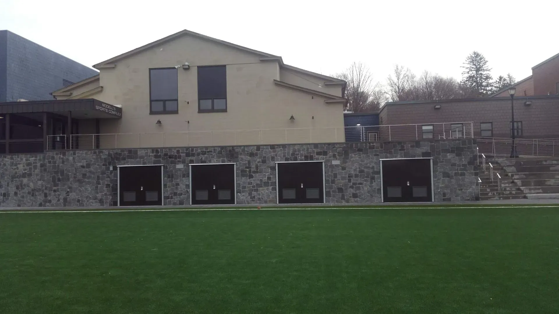 A large building with a lot of windows is sitting on top of a lush green field.
