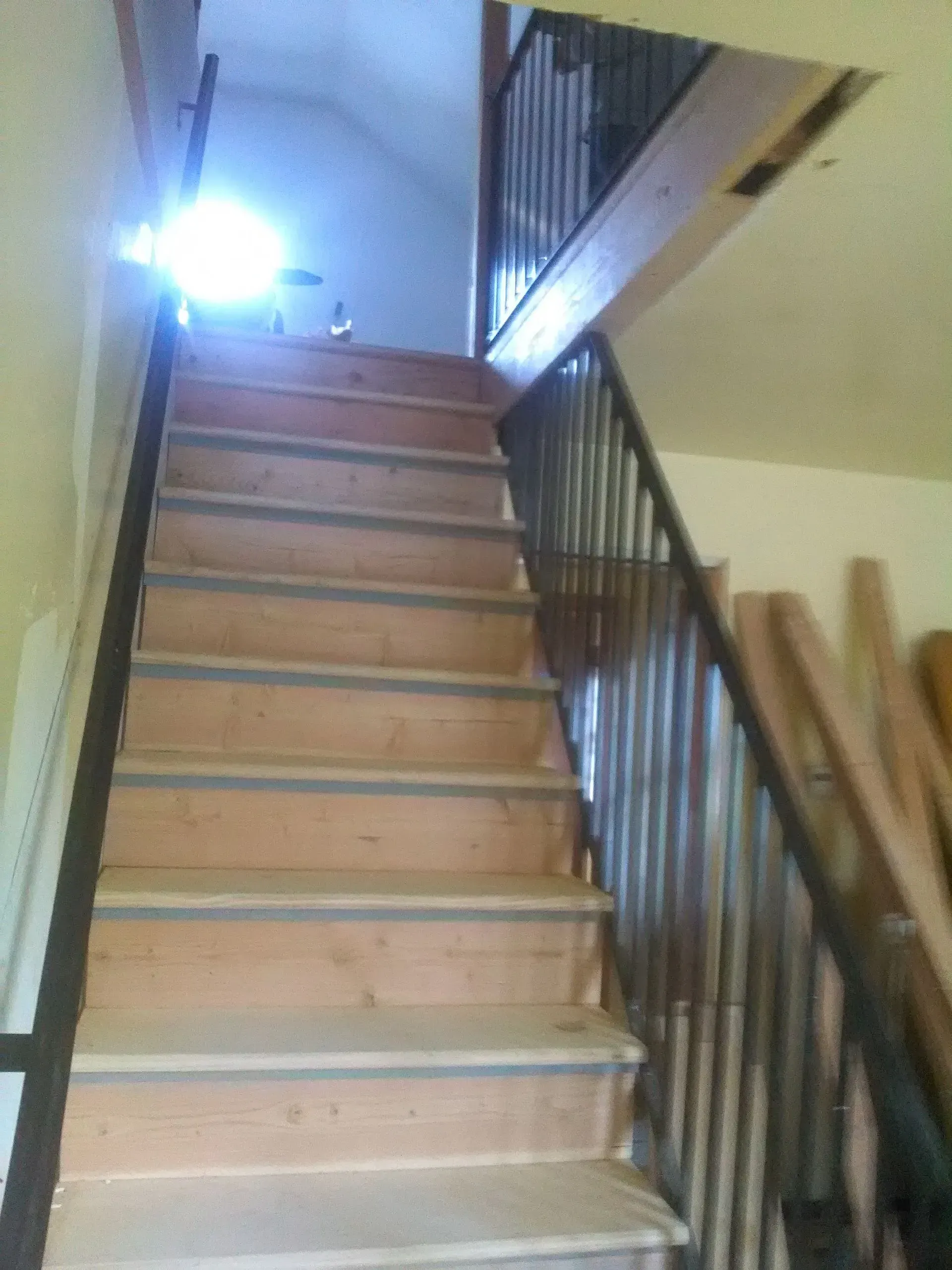A set of wooden stairs with a metal railing.